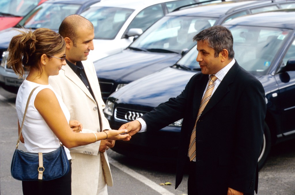 a car dealer shakes hands with clients.