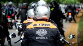 Motorcyclists wearing Harley-Davidson jackets stand on the banks of the Rudolf-von-Bennigsen river during a demonstration ride