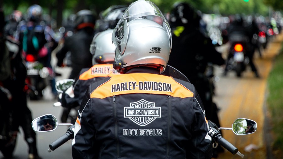 Motorcyclists wearing Harley-Davidson jackets stand on the banks of the Rudolf-von-Bennigsen river during a demonstration ride
