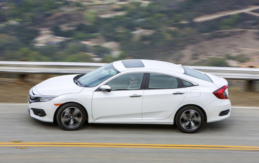 2016 Honda Civic side view from above as it drives on a scenic mountain road 