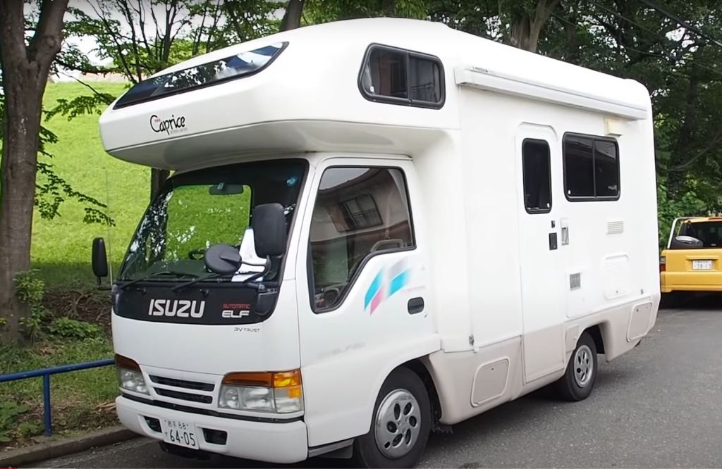 A small, white Isuzu RV is viewed from the front driver's side.