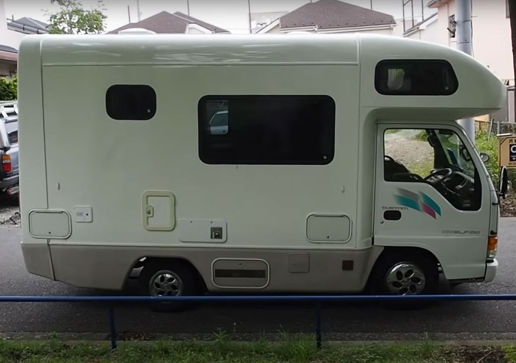 A small, white Isuzu RV is viewed from the front passenger's side.