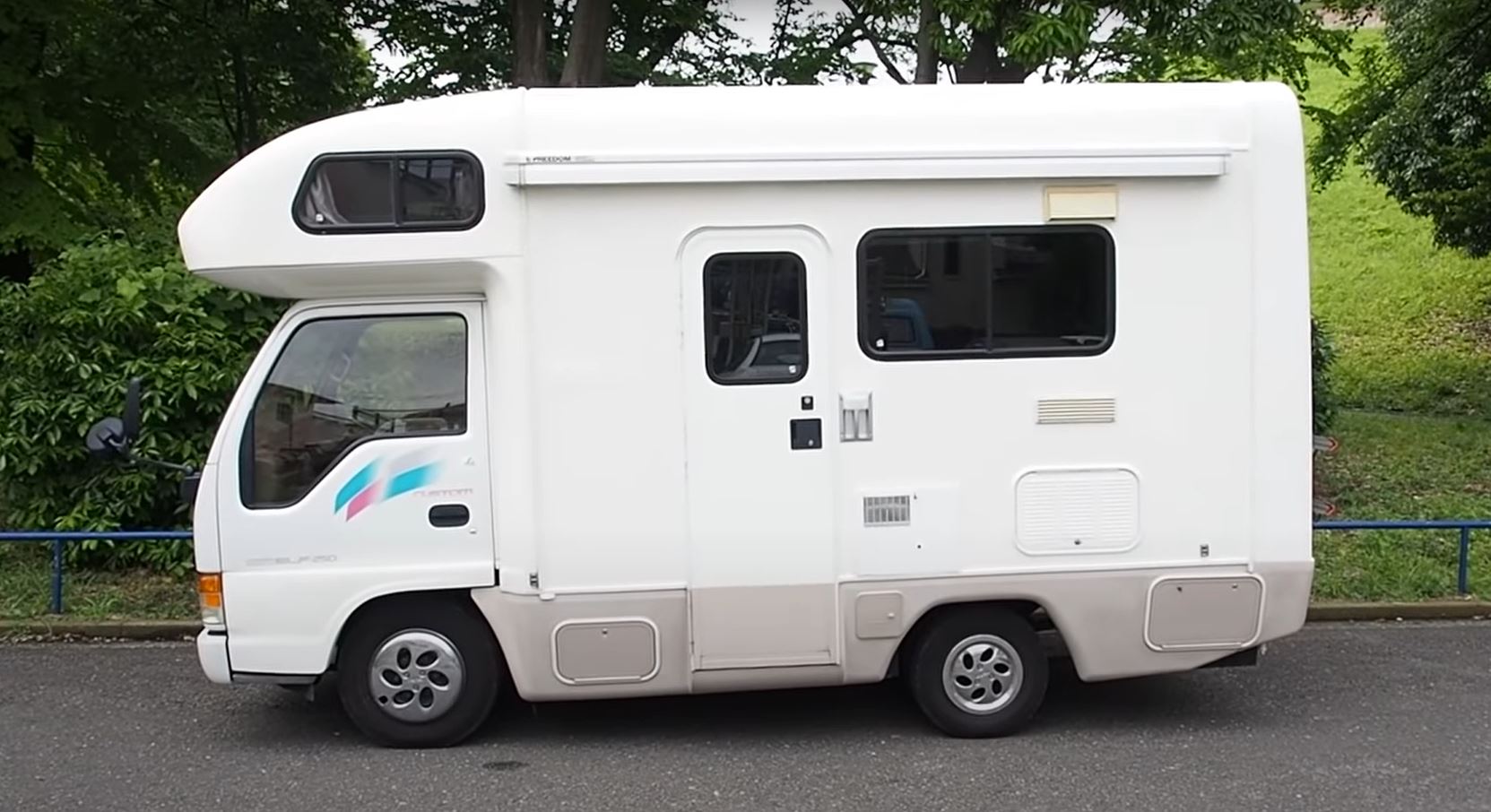 A small, white Isuzu RV is viewed from the driver's side.