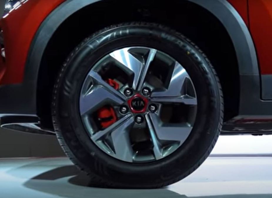 A red brake caliper is tucked in behind a silver wheel with a red accented center cap that says, Kia.
