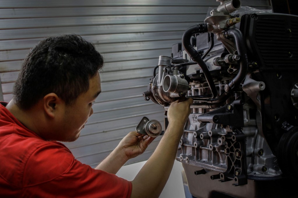 Mechanic tunes up an old Galloper engine for one of the Korean cars
