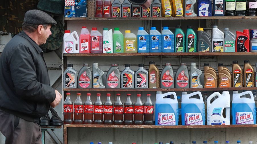 Bottles of different coolant colors on shelves, along with oil and other automotive fluids