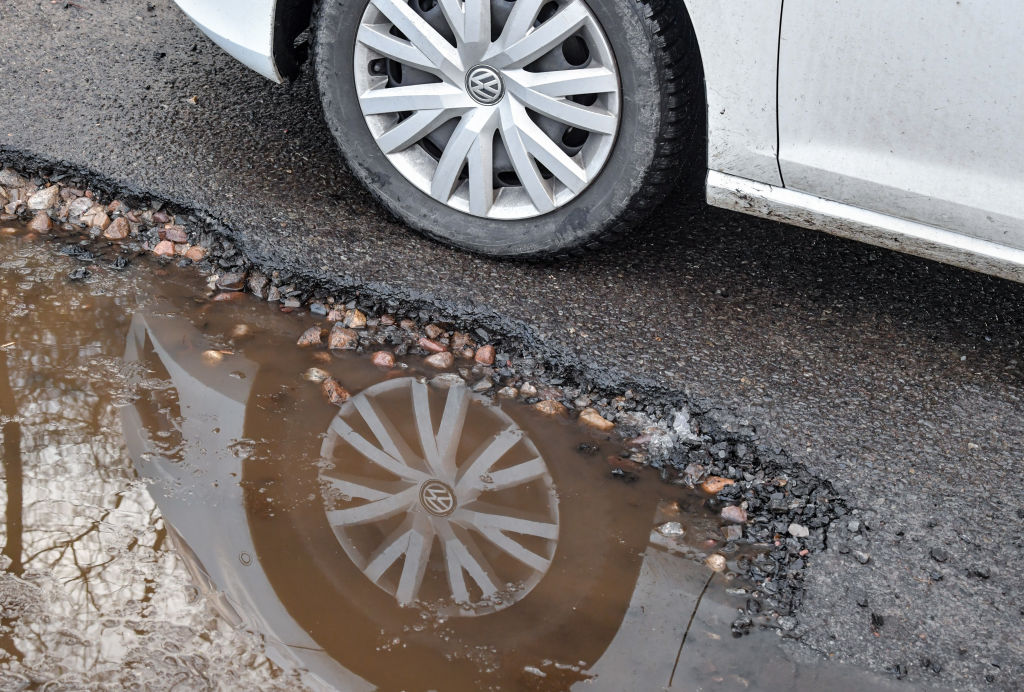 28 January 2019, Brandenburg, Briesen: The car tyre of a Volkswagen can be seen on a defective asphalt road surface and is reflected in a puddle. Photo: Patrick Pleul/dpa-Zentralbild/ZB (Photo by Patrick Pleul/picture alliance via Getty Images)