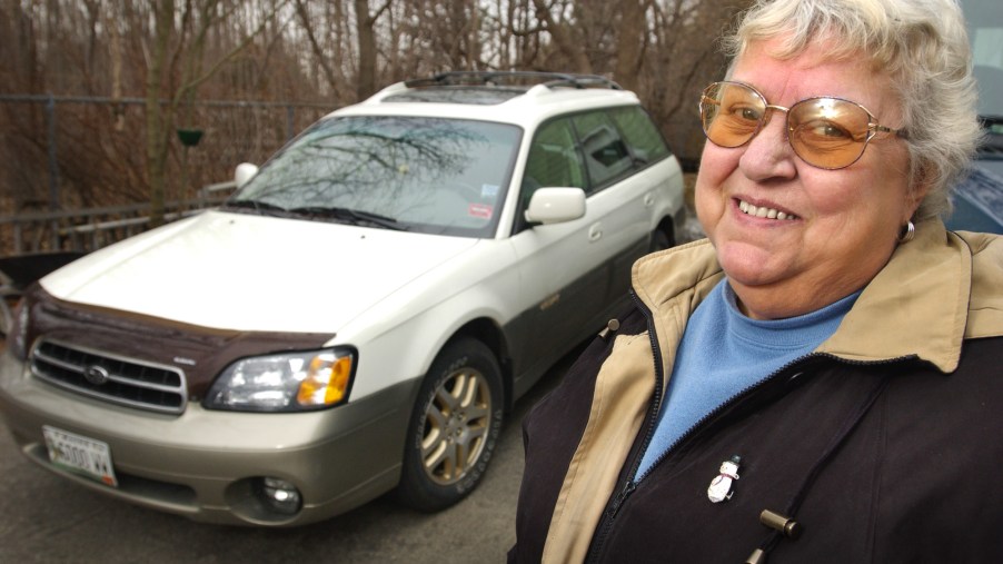 A woman posing for a photo with her Subaru Outback SUV