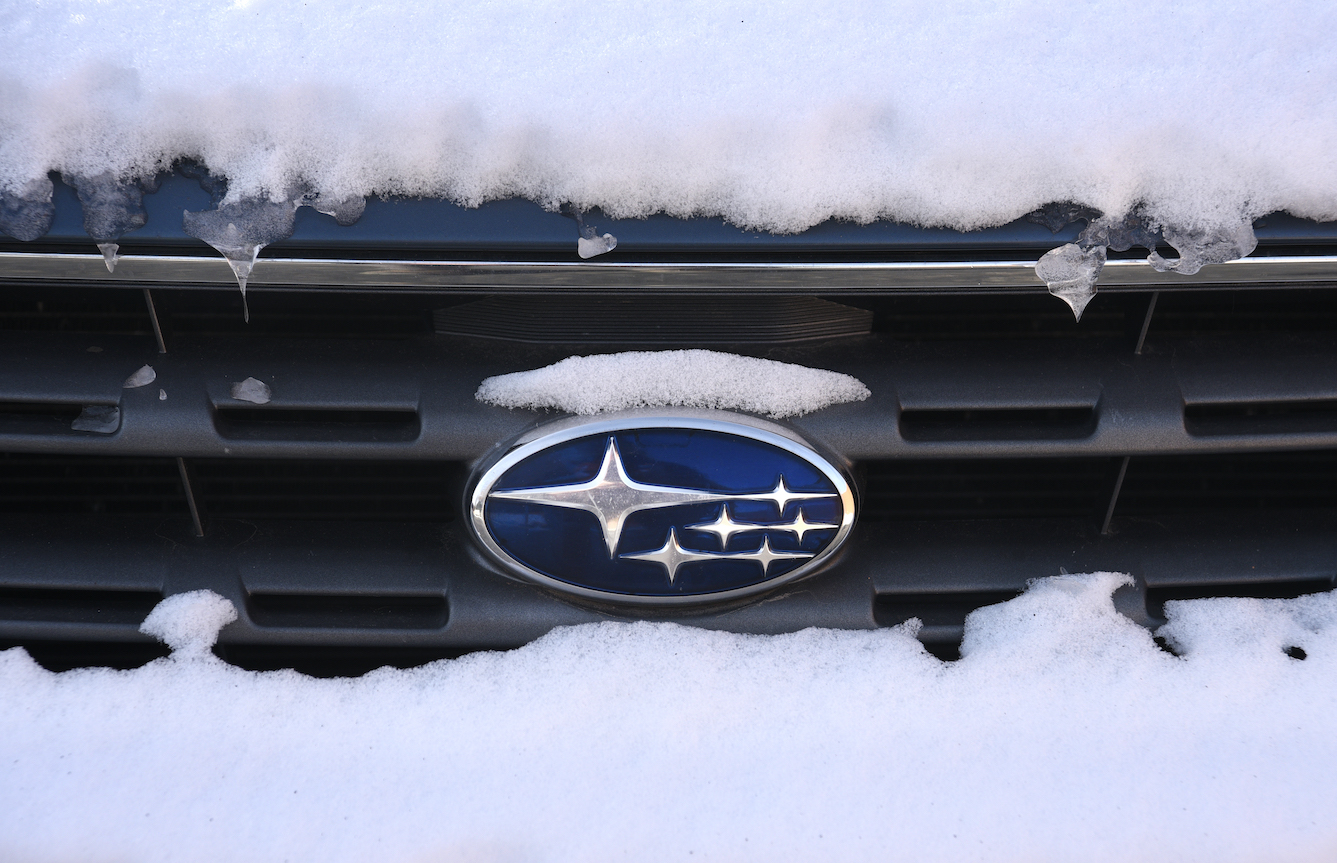The Subaru logo attached to the grill of a snow-covered Subaru Outback in New Mexico.