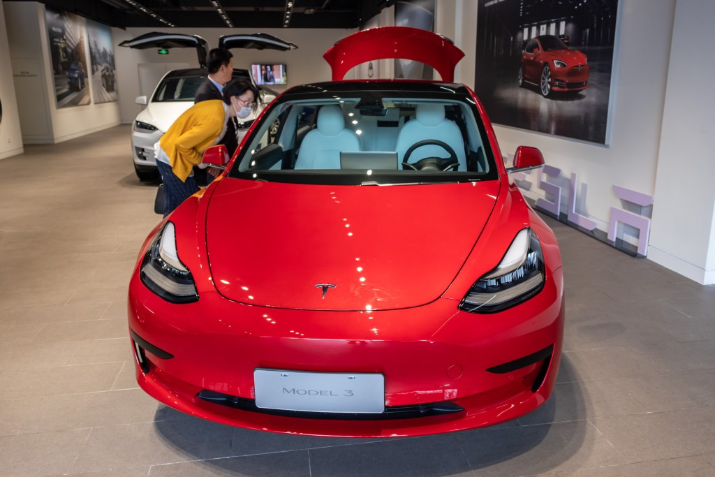 People look at a Tesla Model 3 car at the first Tesla Center in Shanghai