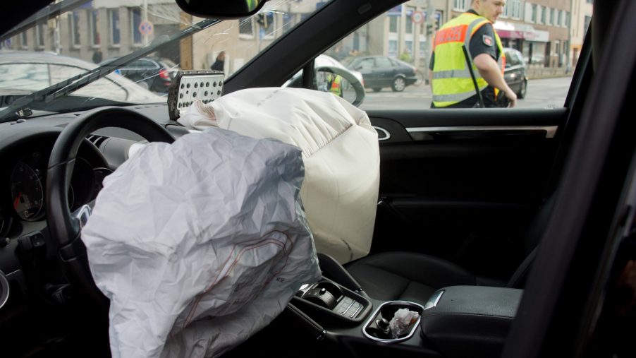 A police officer can be seen through the window of a car that has had two front airbags depoloyed.