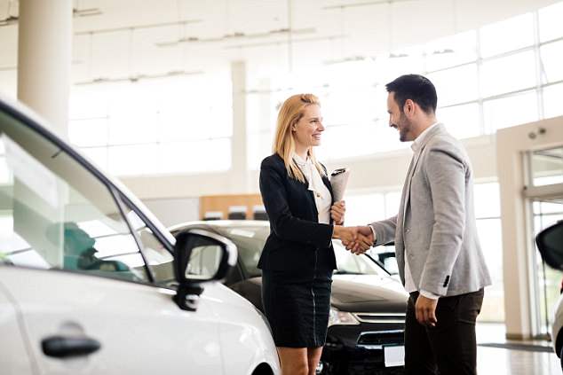 Salesperson showing vehicle to potential customer in dealership 