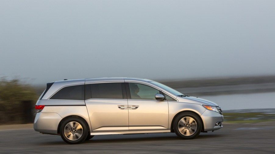 a silver Honda Odyssey driving near the shore. It's a great choice for a used minivan