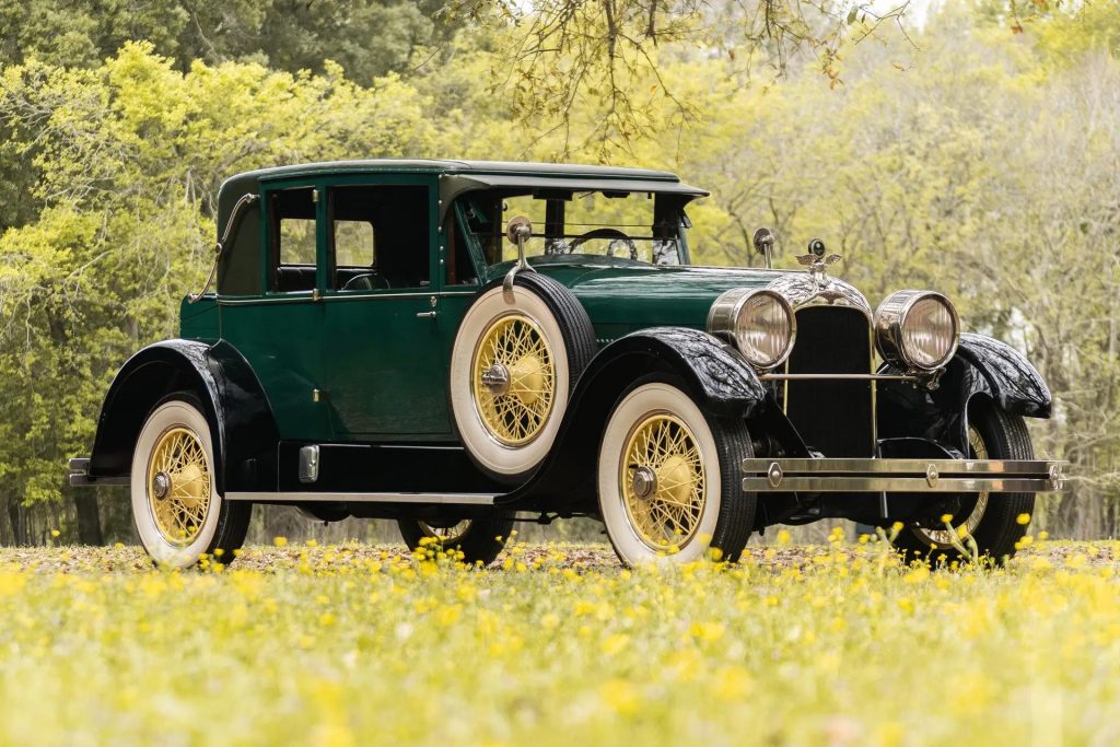 A green 1926 Duesenberg Model A Opera Coupe among yellow flowers