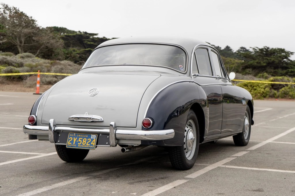 The rear view of a blue-and-silver 1958 MG Magnette ZB Varitone by a beach