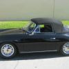 A black 1965 Porsche 356 SC Cabriolet sit by a curb with its black convertible top up.