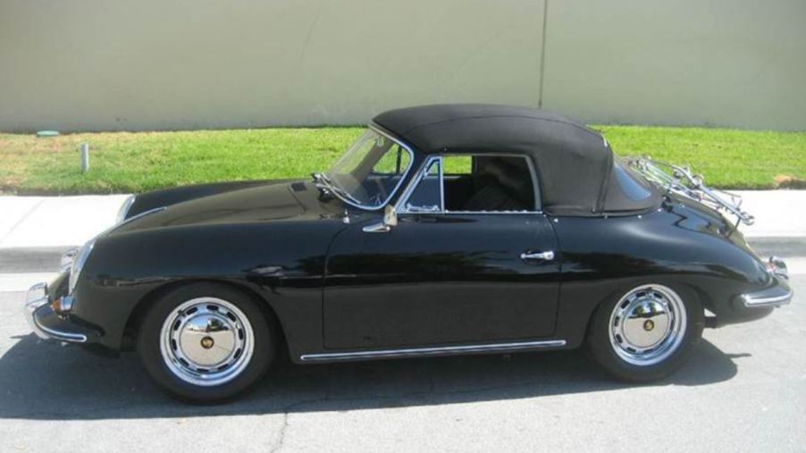 A black 1965 Porsche 356 SC Cabriolet sit by a curb with its black convertible top up.