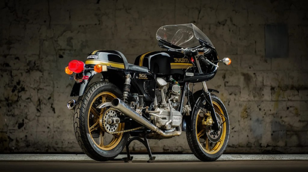 The rear 3/4 view of a black-and-gold 1981 Ducati 900SS Desmo