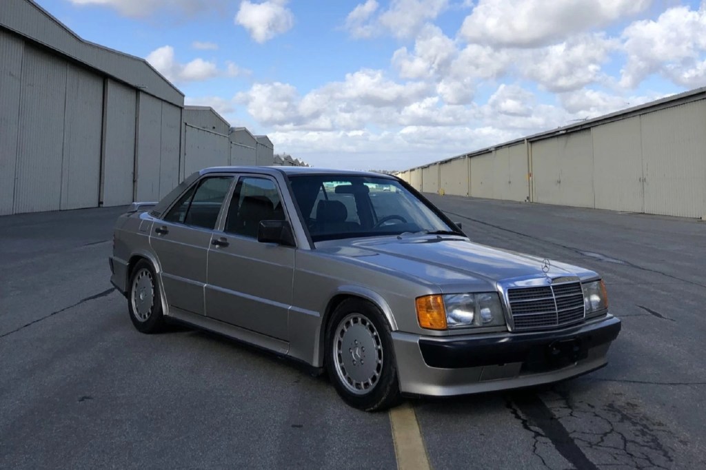 A tan 1986 Mercedes-Benz 190E 2.3-16 parked among storage buildings
