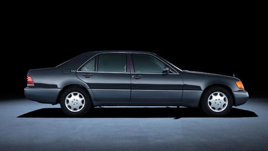 The side view of a black V12-powered 1992 Mercedes-Benz W140 S-Class sedan