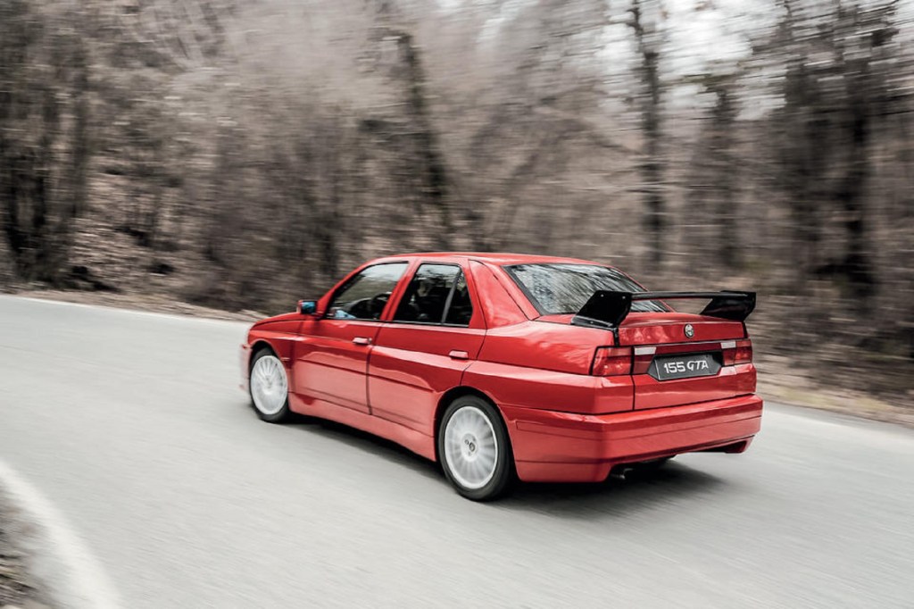 The red 1993 Alfa Romeo 155 GTA Stradale tackles a forested corner