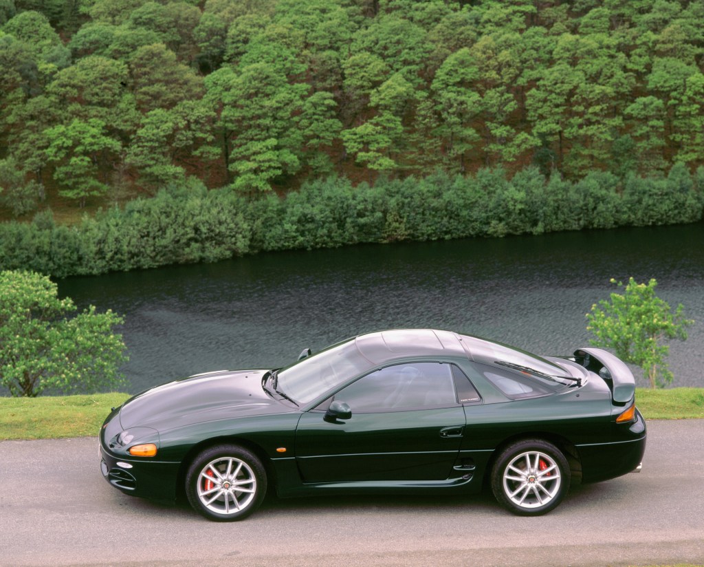 A green 1999 Mitsubishi 3000 GT is parked by a resevoir.