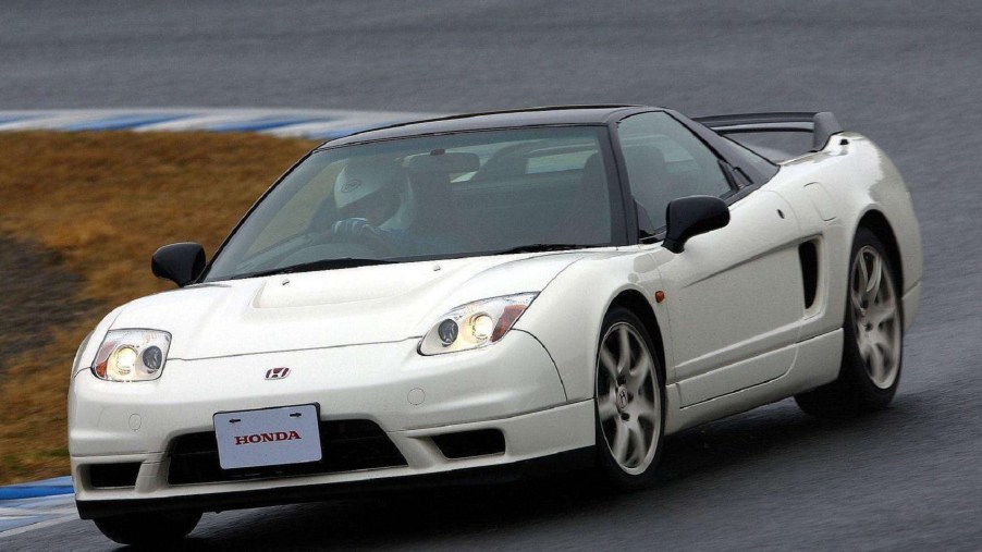 A white 2002 Honda NSX Type R goes around a rainy racetrack corner