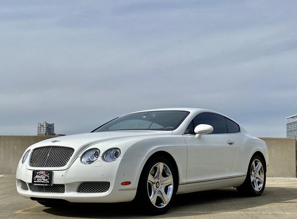 A white 2007 Bentley Continental GT on top of a parking garage