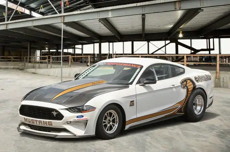 A black-hooded white-and-gold 2018 Ford Mustang Cobra Jet 50th Anniversary Edition in a factory