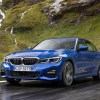 a blue 3 Series at speed on a scenic mountain road.