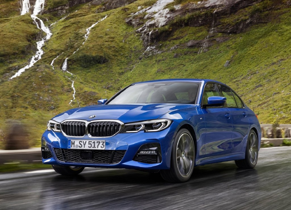 A blue 2019 BMW 3 Series drives on a mountain road