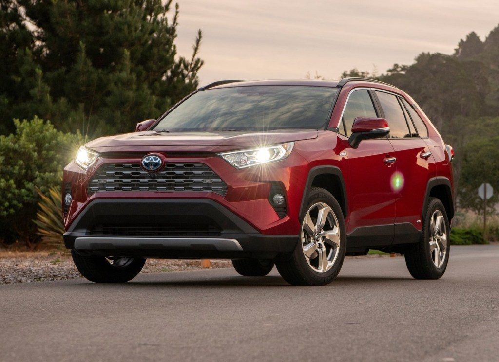 A red 2019 Toyota RAV4 Hybrid at sunset with its lights on
