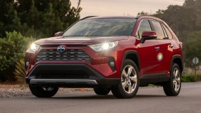 A red 2019 Toyota RAV4 Hybrid at sunset with its lights on