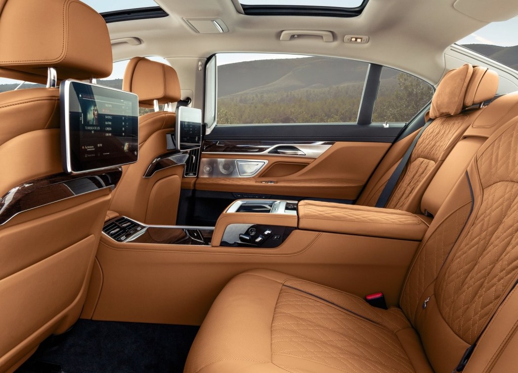 The tan-leather-upholstered rear seats with digital displays of a 2020 BMW 7 Series