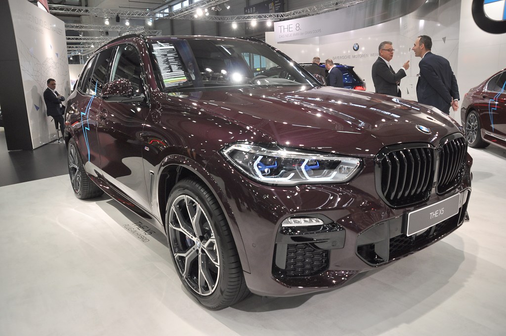 A maroon BMW X5 on display at an auto show