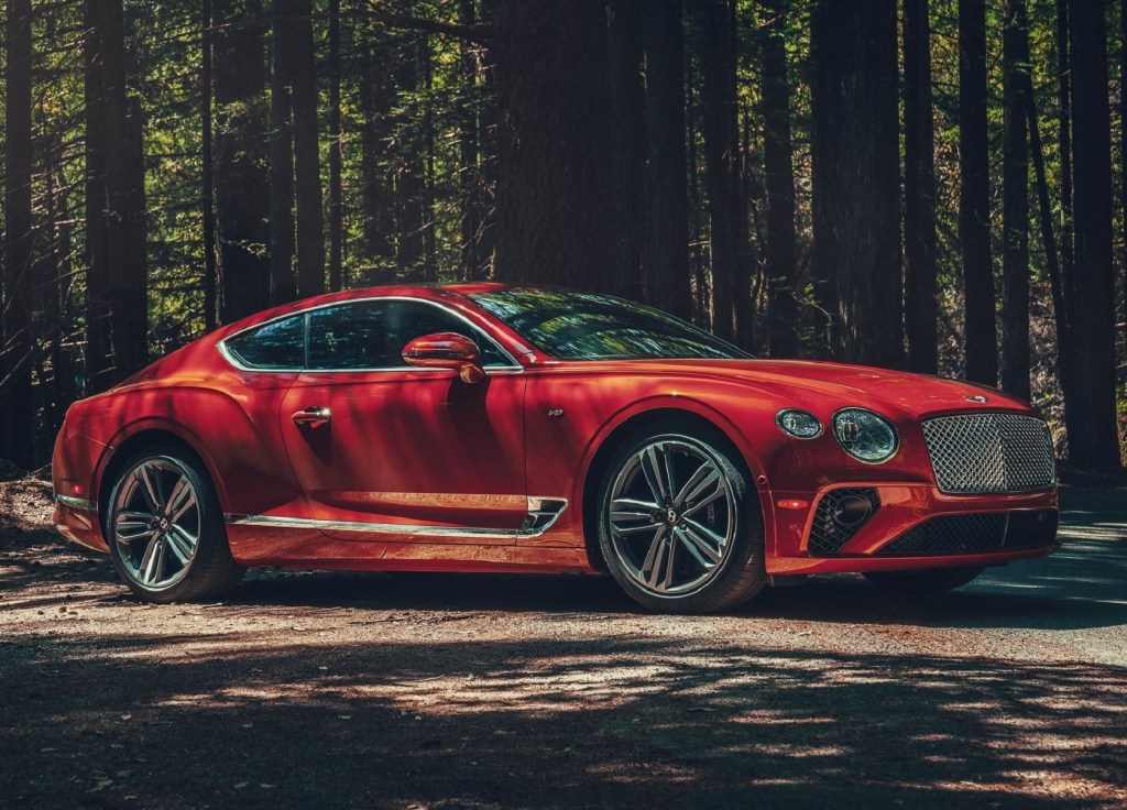 A red 2020 Bentley Continental GT V8 in a shadowy forest