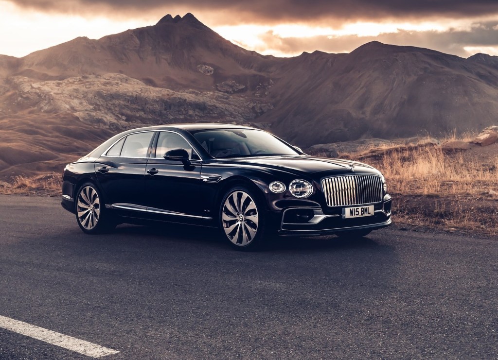 A black 2020 Bentley Flying Spur on a desert road with sunlit mountains behind it