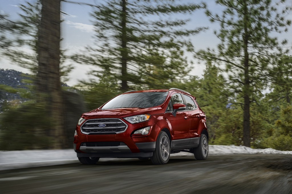 A red 2020 Ford EcoSport Titanium drives through a snowy forest