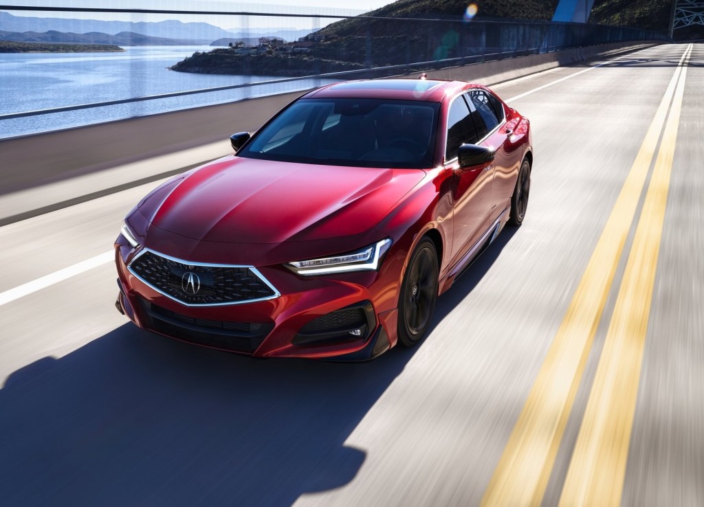 A red 2021 Acura TLX drives on a road over a body of water