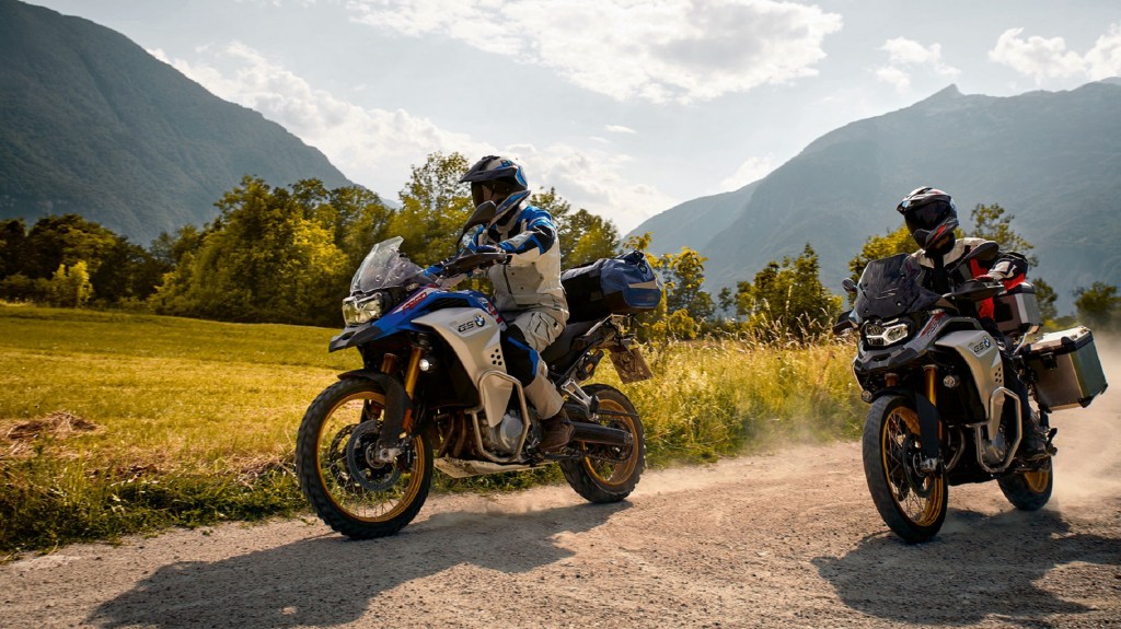 A blue-and-silver and a red-and-silver 2021 BMW F 850 GS Adventure on a mountain gravel trail