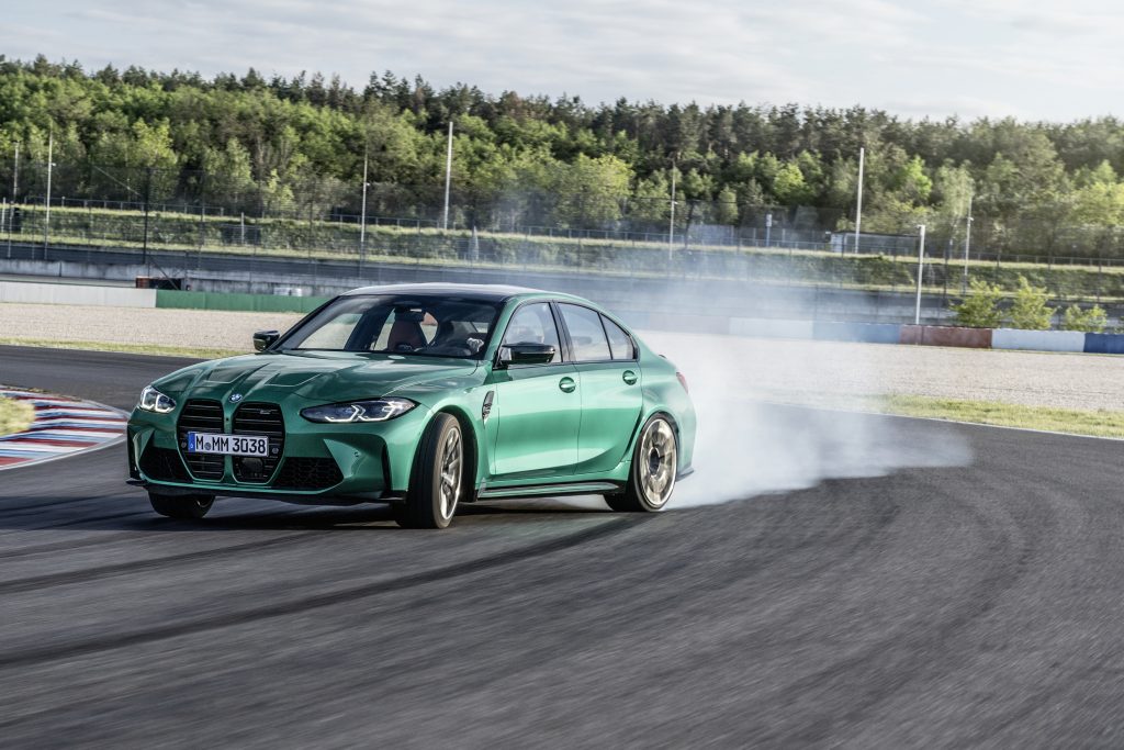The front 3/4 view of a green 2021 M3 sliding around a racetrack