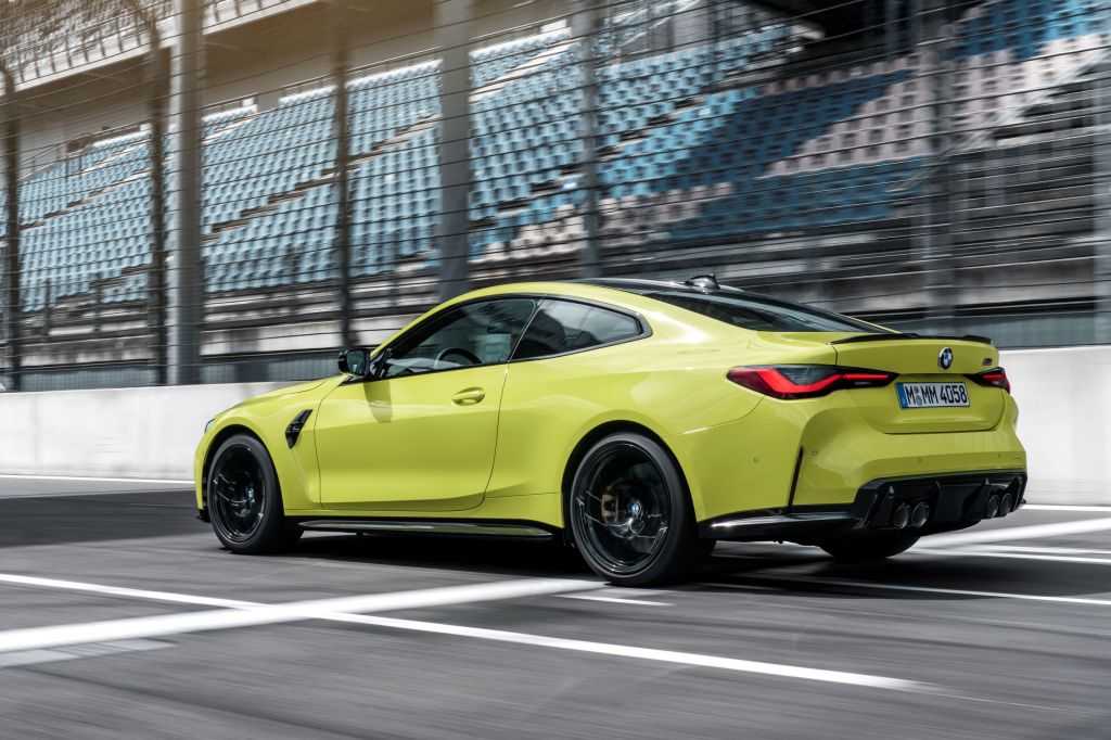 The rear 3/4 view of a yellow 2021 BMW M4 on a racetrack