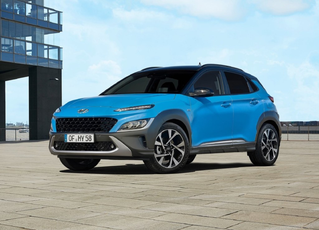 A blue 2021 Hyundai Kona parked next to a modern-looking building