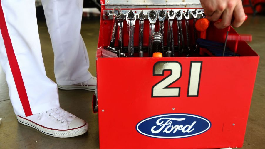 A white-suited NASCAR mechanic reached into their red open toolbox