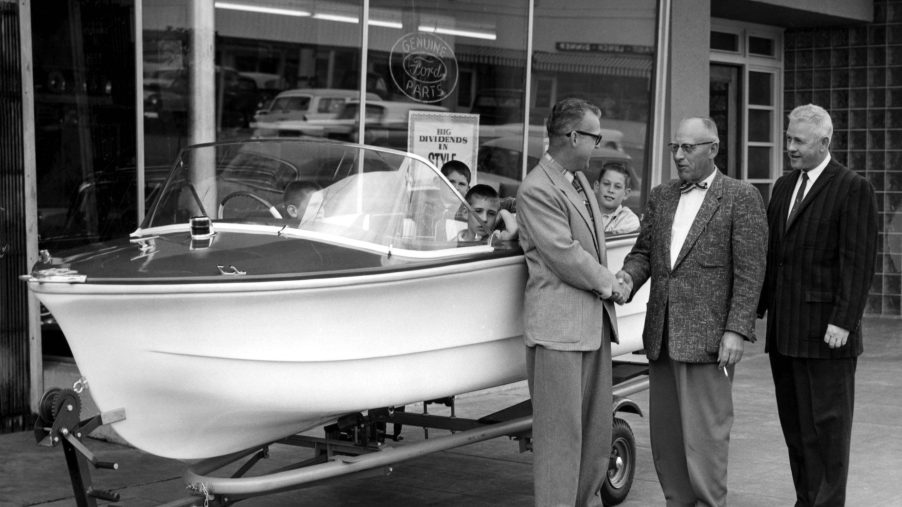 Men shaking hands at boat dealership, 1960s