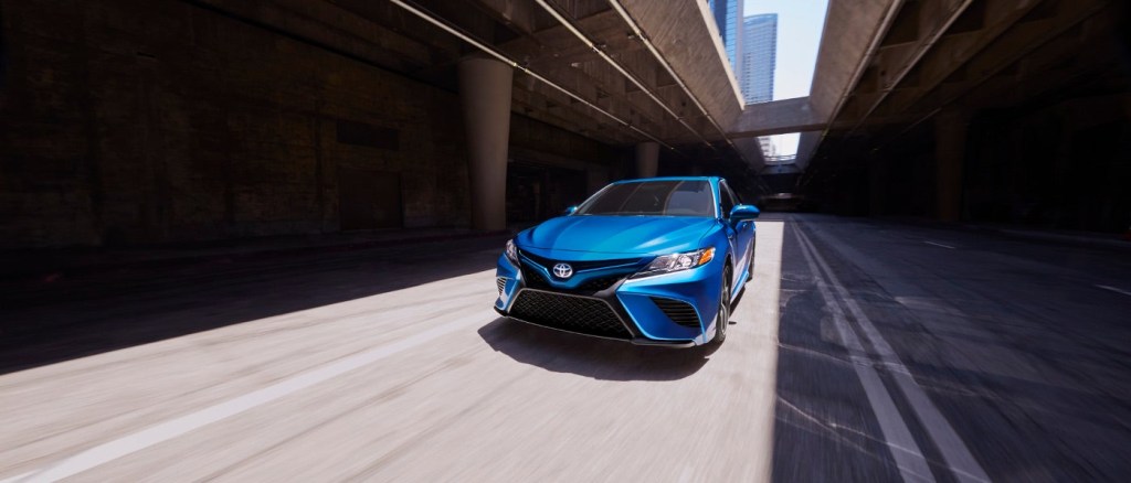 A bright blue 2020 Camry Hybrid whizzing through city streets.