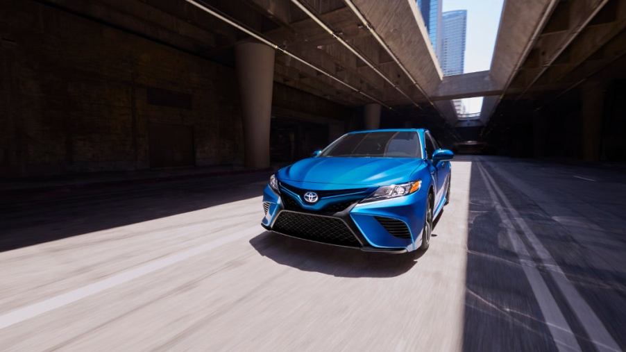 A bright blue 2020 Camry Hybrid whizzing through city streets.
