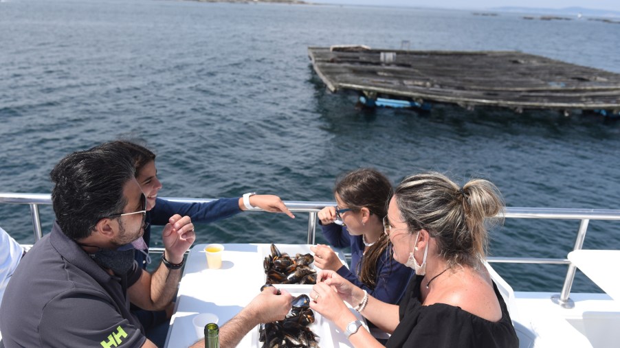 Tourists are seen eating mussels on a tourist boat