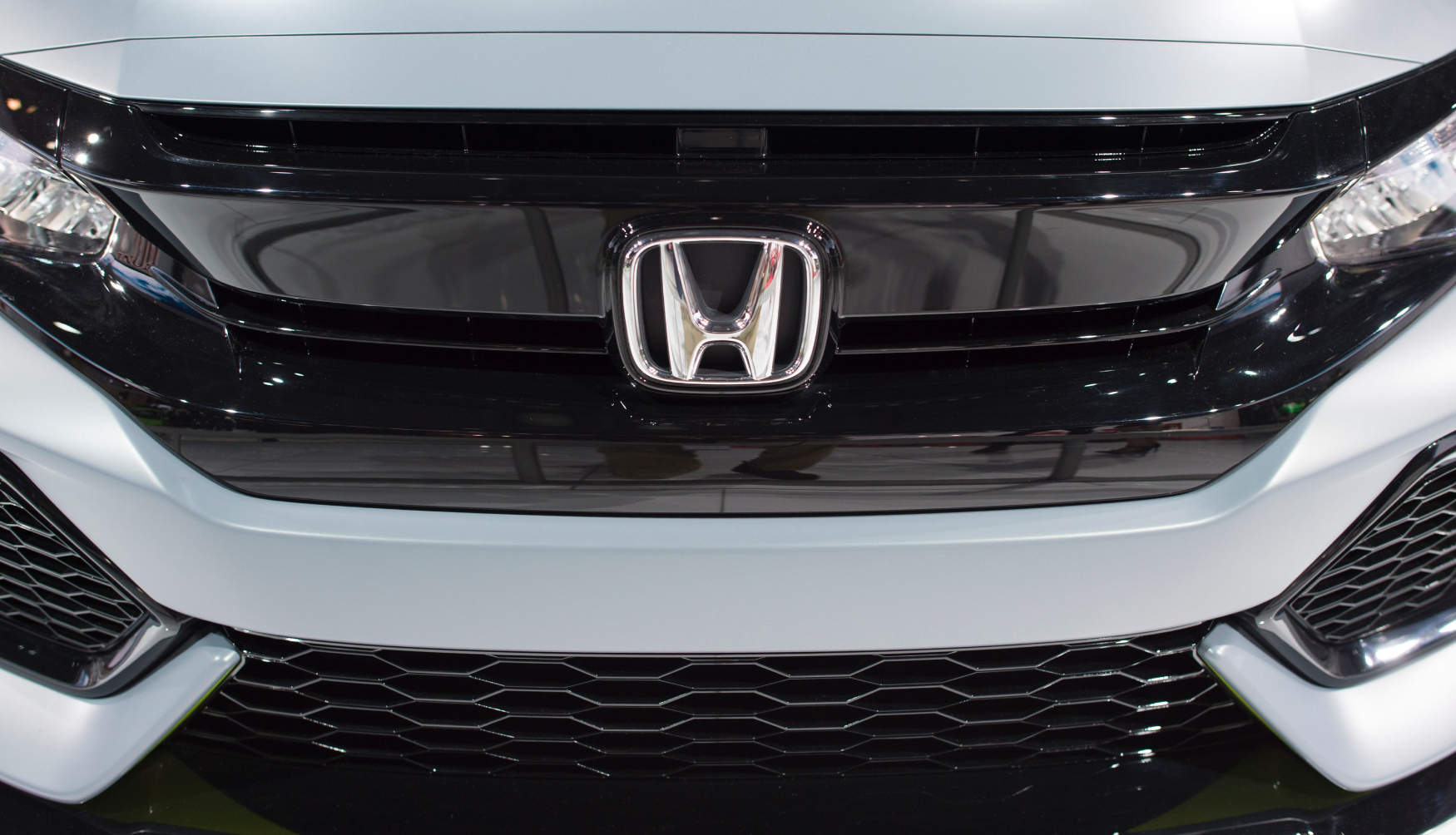 Close up of the Honda logo on the grill of a previous generation of the Honda Civic Hatchback