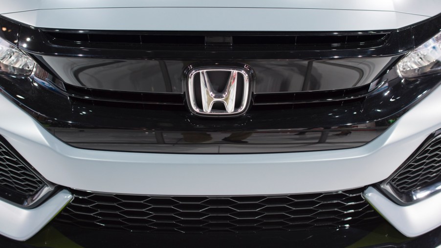 Close up of the Honda logo on the grill of a previous generation of the Honda Civic Hatchback